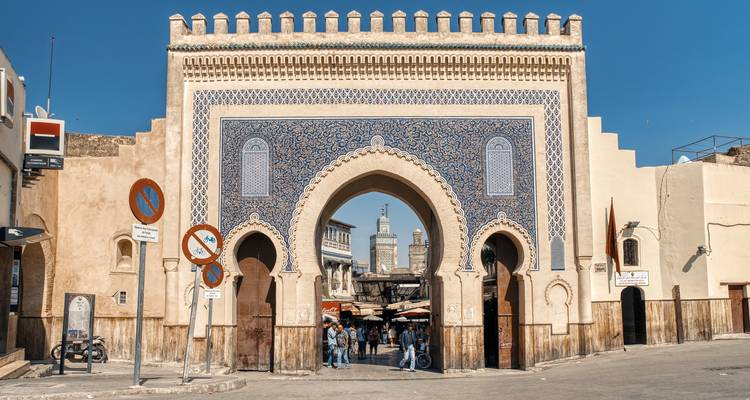 Das verzierte geflieste Tor Bab Bou Jeloud öffnet sich unter klarem blauem Himmel zur Medina von Fès.