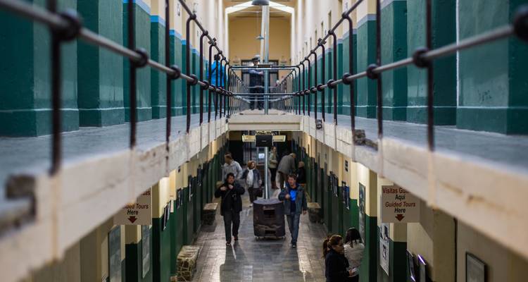 Los visitantes exploran estrechas celdas con paredes verdes dentro de un museo de prisión histórica