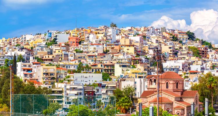 Colorful terraced houses covering a hillside above a small Greek church