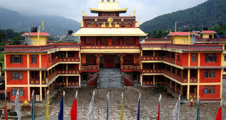Impressive multistorey monastery with golden roof and mountain backdrop.