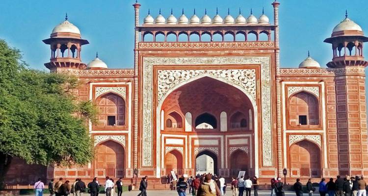 Crowds enter the ornate red sandstone Great Gate leading to the Taj Mahal complex.