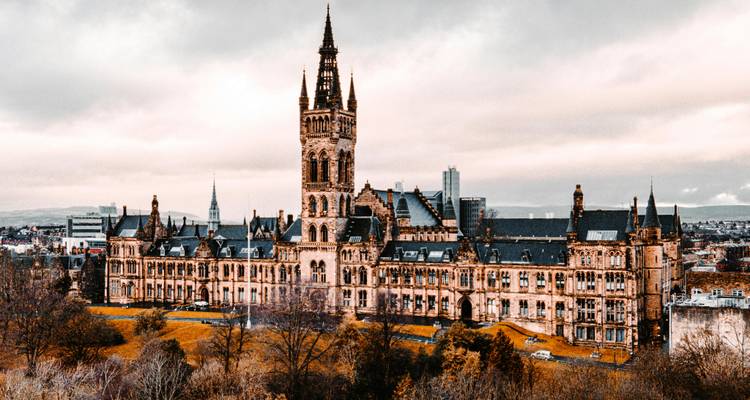 Vue panoramique du bâtiment principal orné de l'Université de Glasgow encadré par les arbres d'automne.
