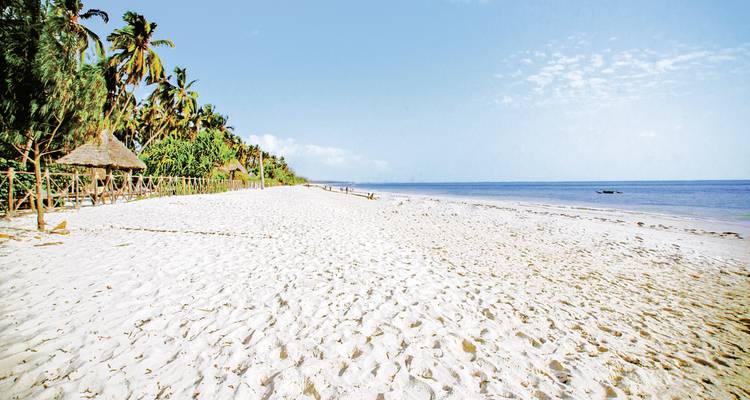 Weitläufiger weißer Sandstrand, der sich bis zum Horizont erstreckt, mit ruhigem blauem Ozean