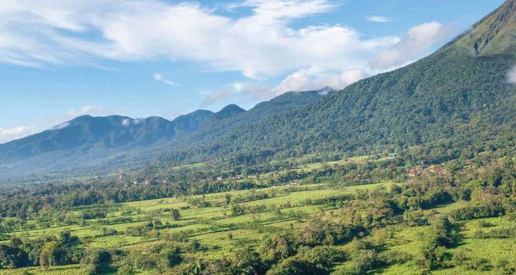 Verdant valley and forested volcanic slopes beneath blue sky in Costa Rica