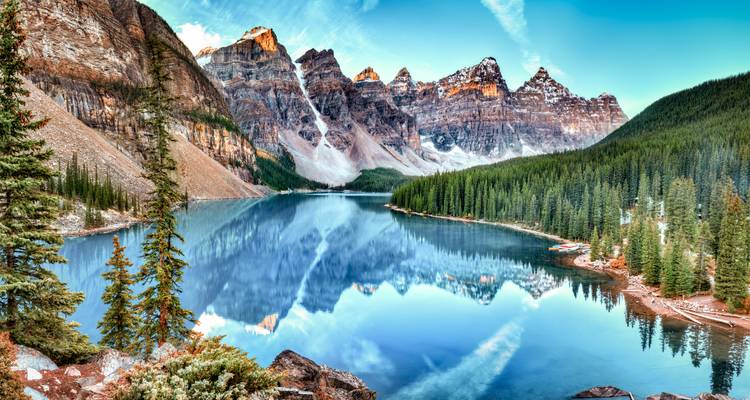 Stunning panorama of Moraine Lake reflecting ten snow-dusted peaks and evergreen valley in Banff National Park.