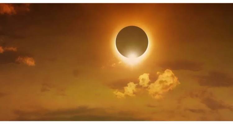 Éclipse solaire spectaculaire avec une couronne brillante se détachant sur un ciel doré et de petits nuages
