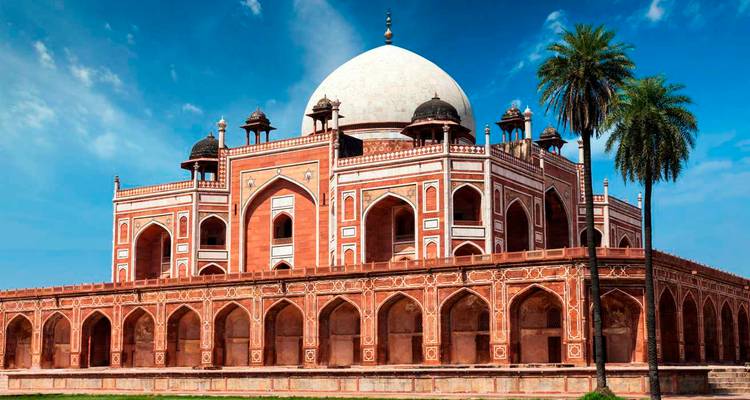 La Tumba de Humayun en Delhi enmarcada por cielos azules y palmeras