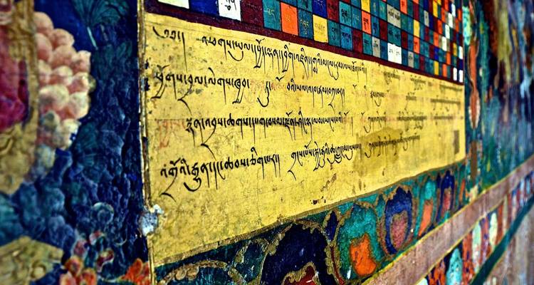 Colorful wall mural of Tibetan script and symbols inside a monastery