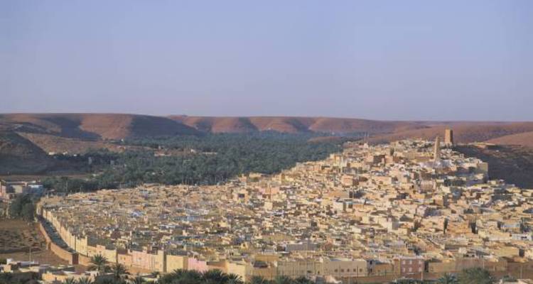 Panoramic view of Ghardaia’s densely packed beige houses stretching along an oasis in the M'Zab valley.