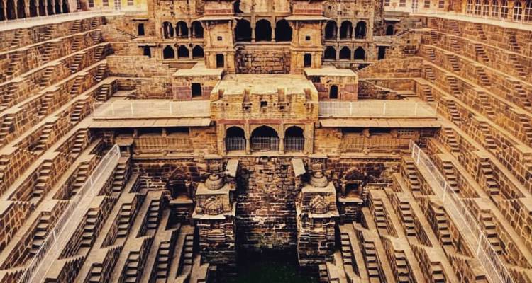Symmetrical stone steps descend deep into the dramatic Chand Baori stepwell.