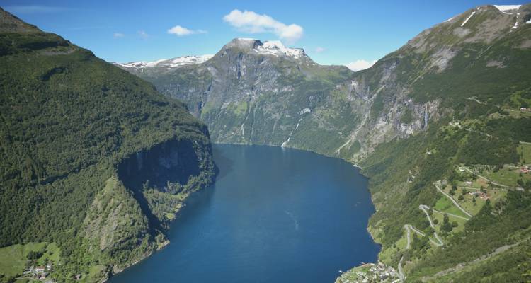 Le majestueux Geirangerfjord s'enfonçant profondément entre des montagnes imposantes aux pics enneigés et des falaises verdoyantes.