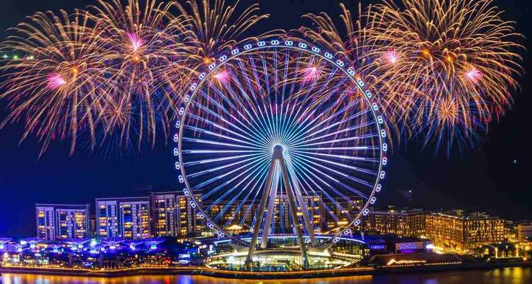 Das riesige Riesenrad Ain Dubai erleuchtet mit lebhaften Feuerwerken über der Uferpromenade bei Nacht.