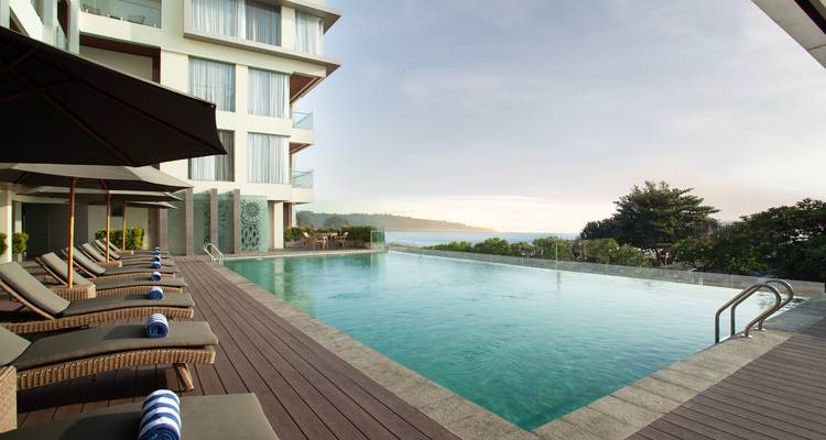 Infinity-Pool-Terrasse mit Blick auf den Ozean in einem luxuriösen Küstenhotel in der Morgenröte.