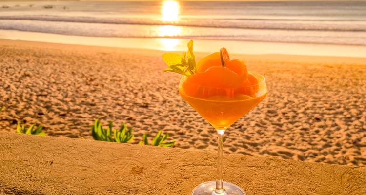 Erfrischender tropischer Cocktail vor einem goldenen Sonnenuntergang am Strand.