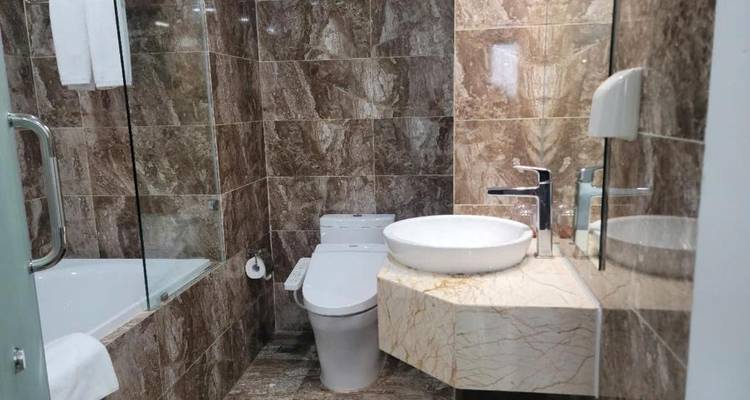Modernes Hotelbadezimmer mit Marmorfliesen, das eine Badewanne, eine Toilette und ein Aufsatzwaschbecken bietet.