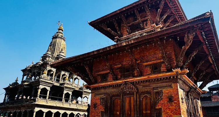 Red-brick pagoda and a neighbouring stone temple rise against a clear blue Kathmandu sky.