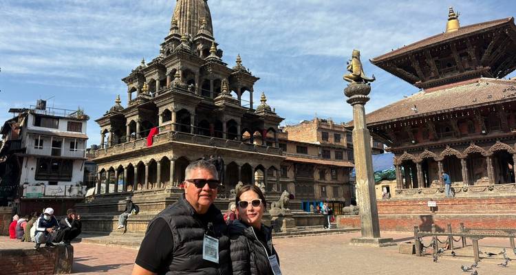 Two travellers pose in front of elegant sandstone temples in Patan Durbar Square.