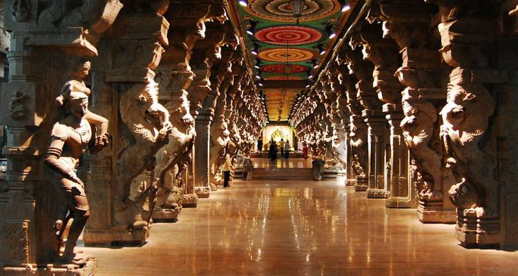 An ornate pillared hallway with carved stone figures and colorful ceiling mandalas stretches into the distance.