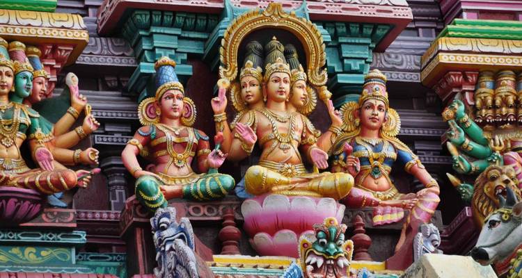 Close-up of multicolored Hindu deities carved in high relief on a temple tower.