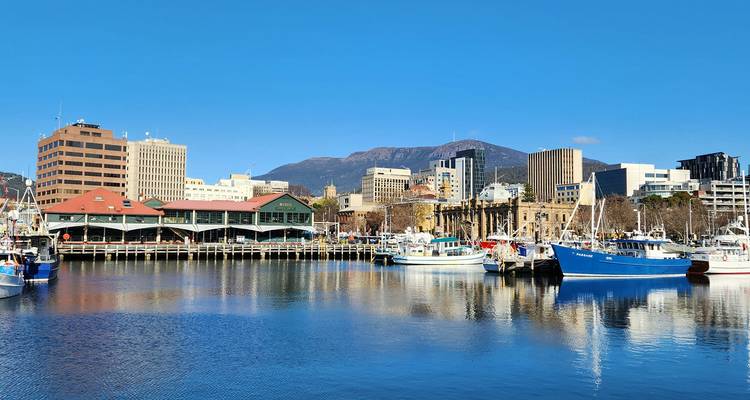 Waterfront of Hobart with fishing boats, colourful buildings and Mount Wellington under a bright blue sky