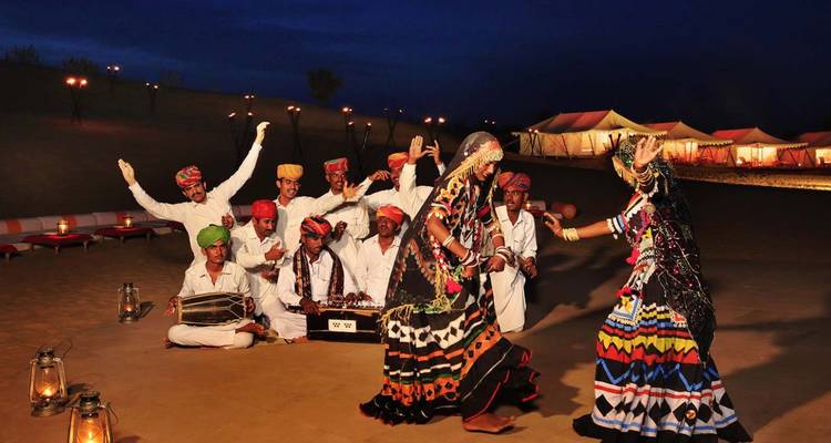 Traditional Rajasthani musicians and dancers perform in colourful dress at a desert camp after dark