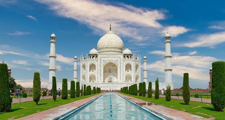 Iconic frontal view of the Taj Mahal mirrored in the long reflecting pool against a bright blue sky