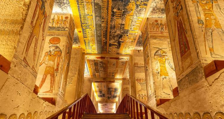 Lebhaft bemalte Hieroglyphenwände und -decken schmücken eine schmale Treppe tief in einem ägyptischen Grab.