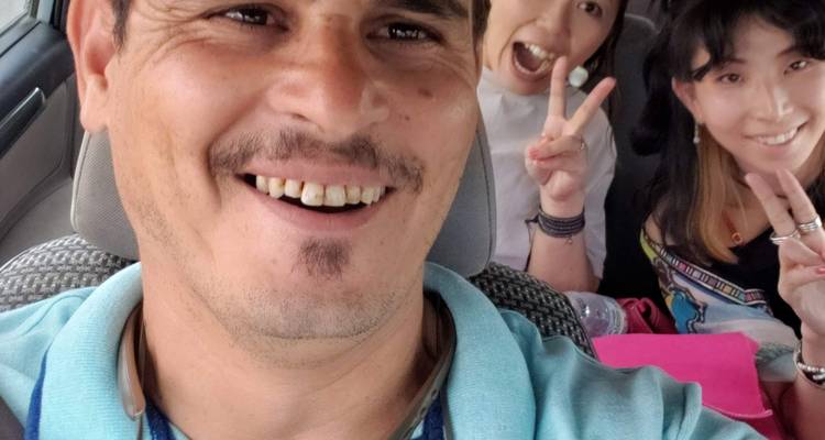 Fun car selfie of guide and passengers making peace signs.