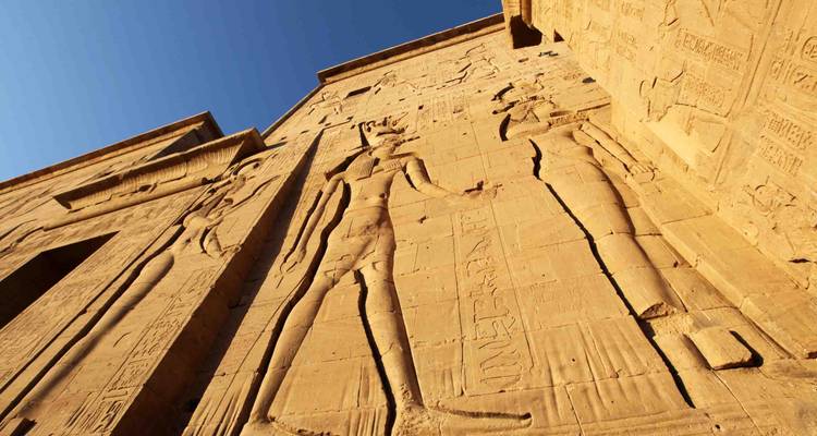 Lage-hoekweergave van gedetailleerde reliëfs uitgesneden in de zonovergoten zandstenen muren van een oude Egyptische tempel
