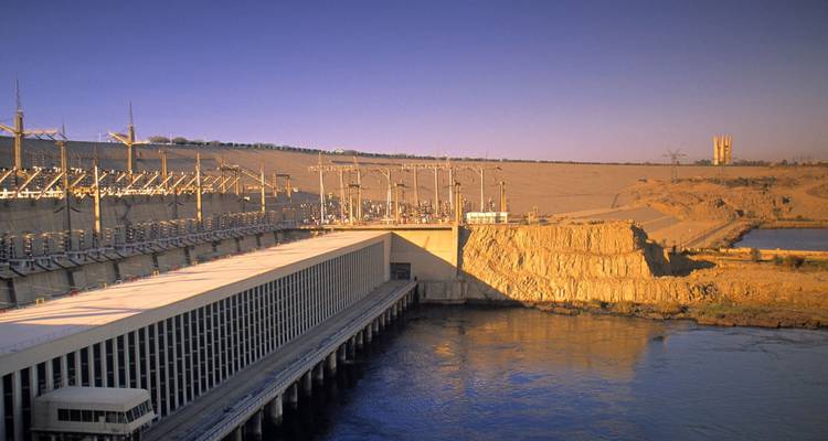 Wide view of Aswan High Dam and power station beside the Nile under clear sky.