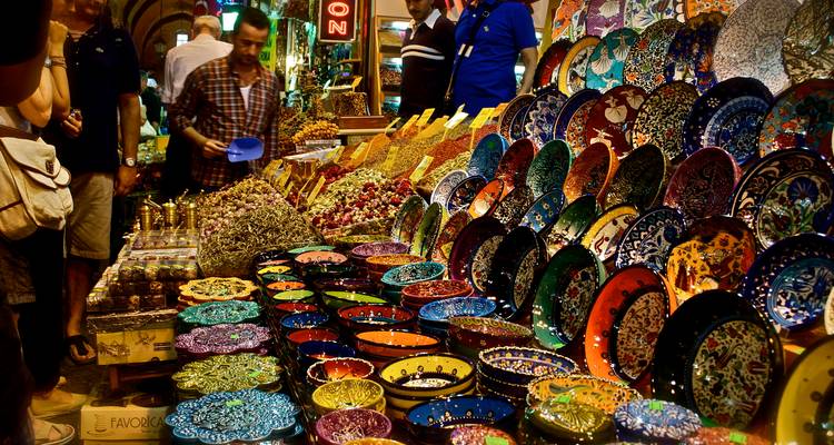 Vibrant market stall packed with colorful ceramic plates and spices under warm lights.