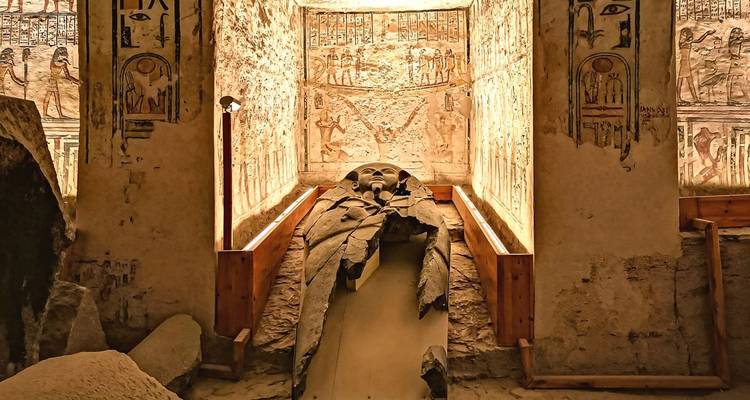 An illuminated ancient sarcophagus in a richly painted tomb chamber.