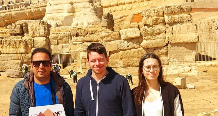 Three travellers standing before the Sphinx and weathered limestone blocks.