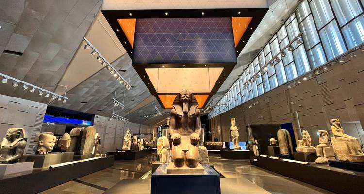 Well-lit gallery of ancient statues framed by striking modern architecture.