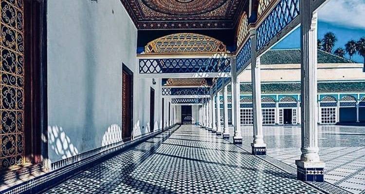 Largo corredor embaldosado con columnas blancas y suelo con patrones en el Palacio de Bahía bajo un cielo azul brillante.