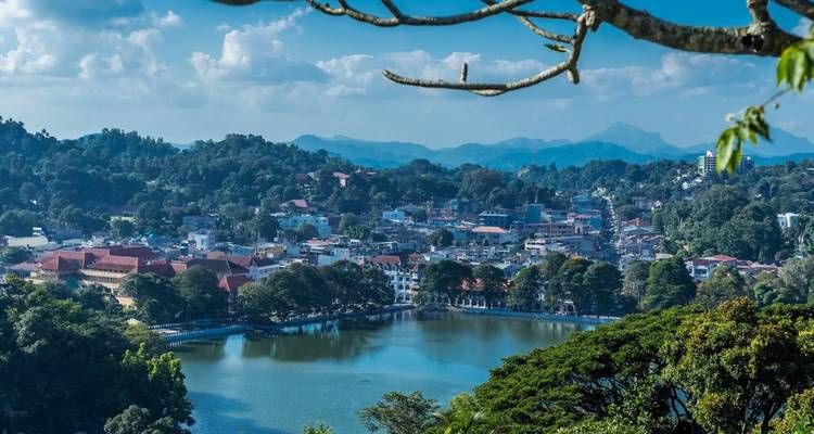 Malerischer Blick über den Kandy-See und die umliegende Stadt, eingerahmt von Ästen und sanften Hügeln.