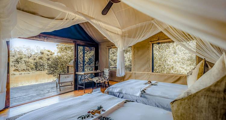 Luxury tented bedroom with nets open to a deck overlooking a tranquil river
