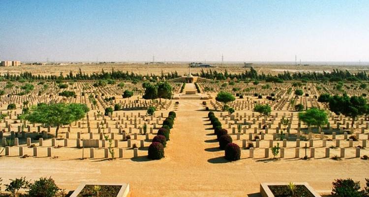 Expansive, symmetrical desert cemetery with rows of uniform headstones stretching to the horizon.