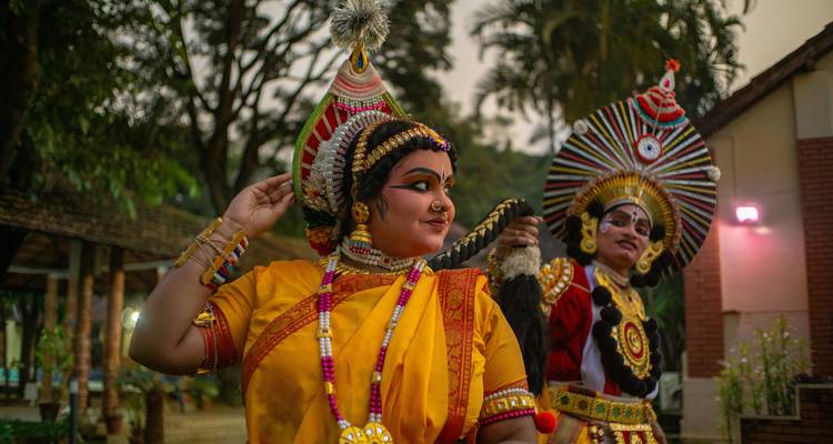 Traditional Kerala dancers in vibrant costume and makeup performing outdoors in evening light.