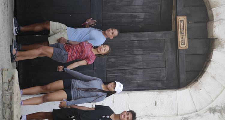Family holding hands while exiting through the historic 'Door of Return' at a coastal fort
