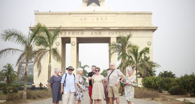Group of seniors posing in front of Accra’s Independence Arch surrounded by palms.
