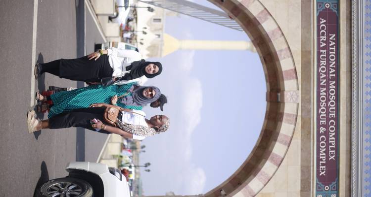 Three women pose beneath the archway of Accra’s National Mosque Complex on a sunny morning.