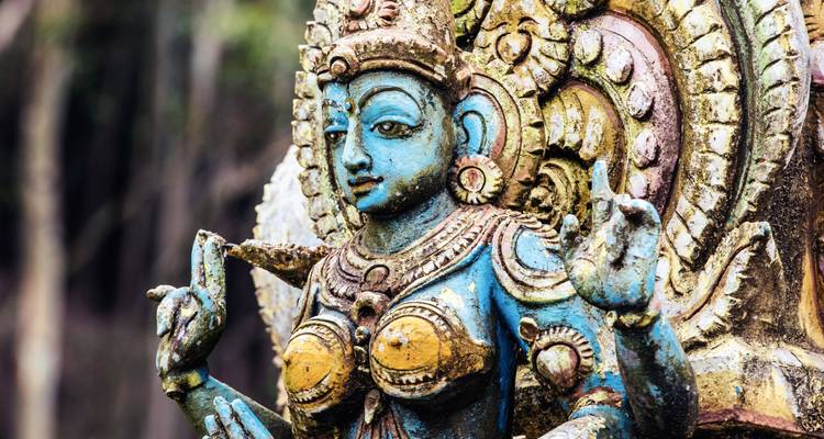 Gros plan d'une statue de divinité hindoue peinte de manière complexe avec des bleus et des ors vibrants.
