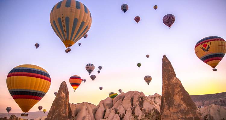 Hot-air balloons rising over the spired rock formations of Cappadocia at dawn.