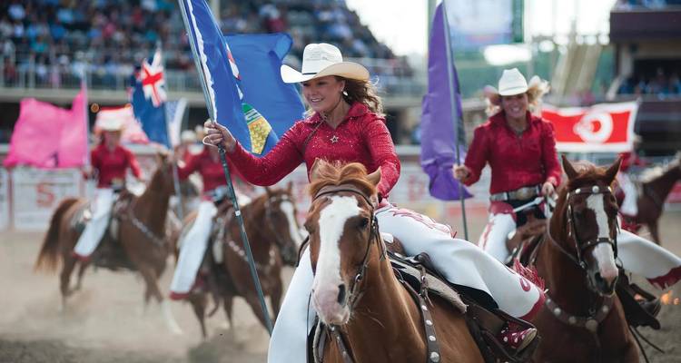 Riders in red sequin uniforms perform horseback flag routine at Calgary Stampede