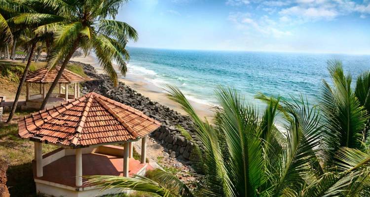A seaside gazebo with terracotta roof overlooks a tranquil sandy beach fringed by palms.