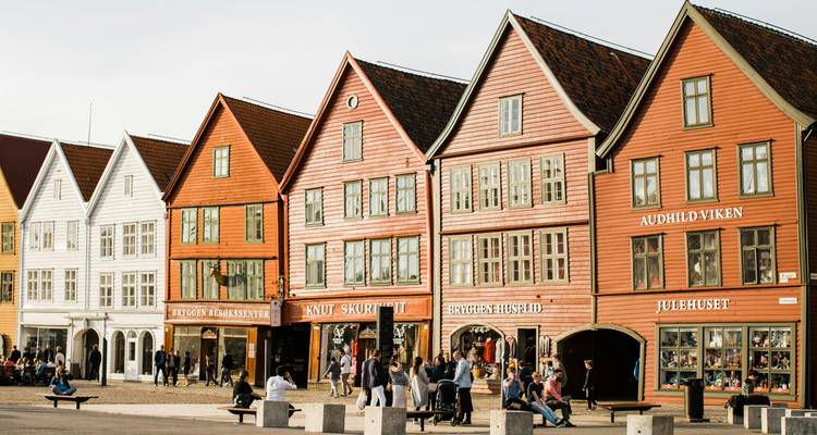 Les piétons flânant devant les maisons en bois de Bryggen à la lumière chaude de l'après-midi