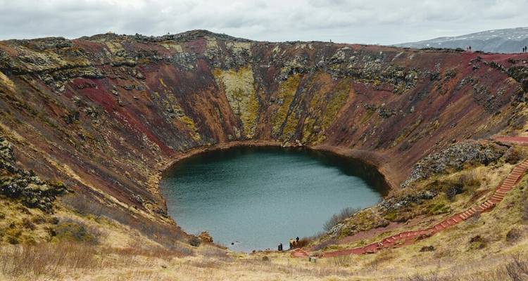 Le cratère volcanique Kerið aux teintes colorées avec un lac bleu profond entouré de pentes rouille en Islande.