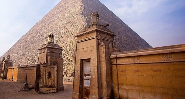 Great Pyramid of Giza with stone gatehouses in the foreground under hazy sky