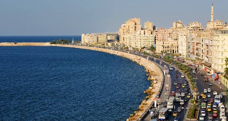 Sweeping coastal cityscape with busy seaside highway curving beside deep blue Mediterranean.